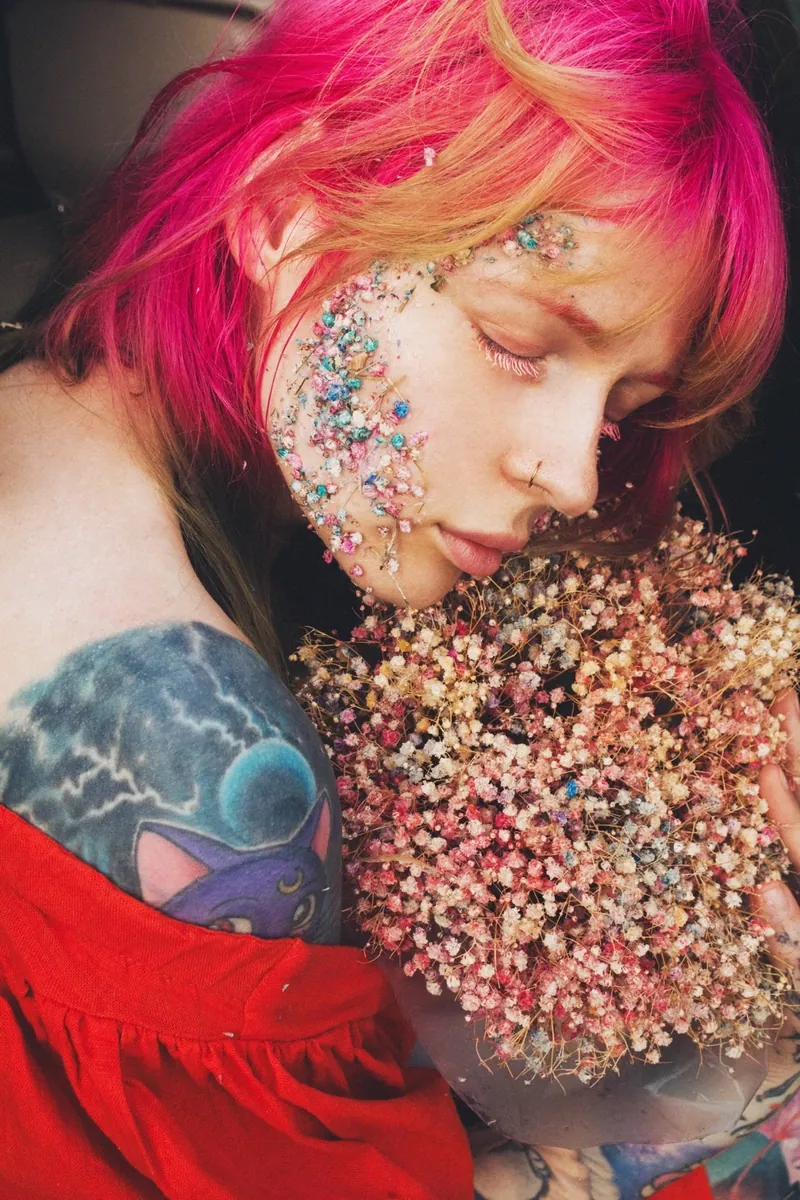 Portrait of Kristina Vishar with pink hair and a blue cat shoulder tattoo