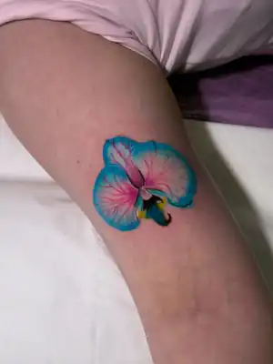 Colour orchid thigh tattoo by Kristina Vishar