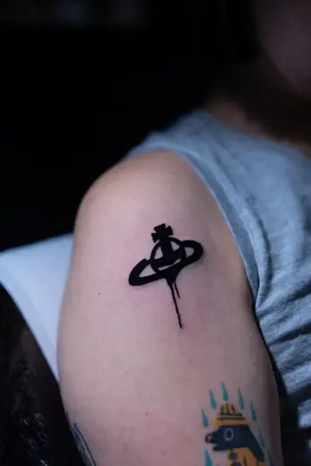 Small black symbol upper arm tattoo by Kristina Vishar