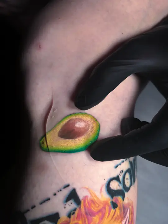 Tiny colour avocado tattoo by Kristina Vishar