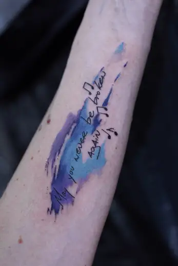 Small watercolour and script forearm tattoo by Kristina Vishar